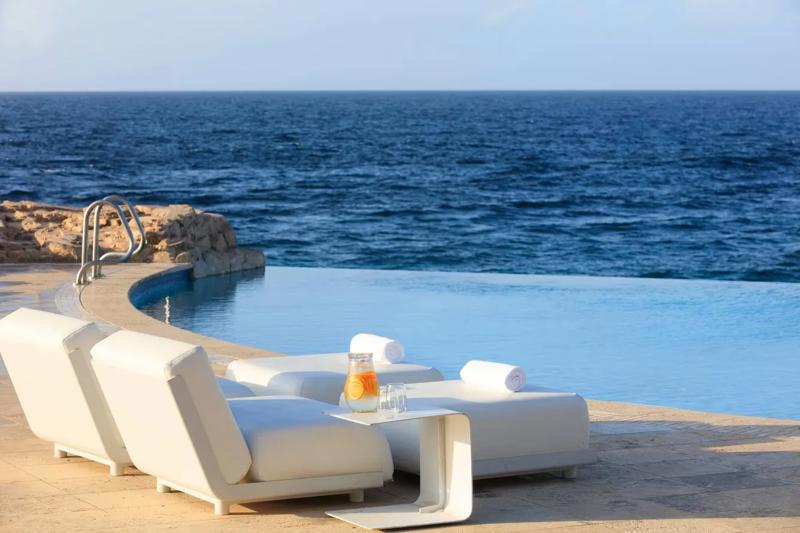 Piscină infinity cu șezlonguri albe și vedere panoramică la ocean – Renaissance Curaçao Resort