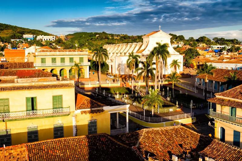 Vedere de ansamblu asupra Plazei Mayor cu biserica albă și acoperișuri de teracotă, Trinidad, Cuba